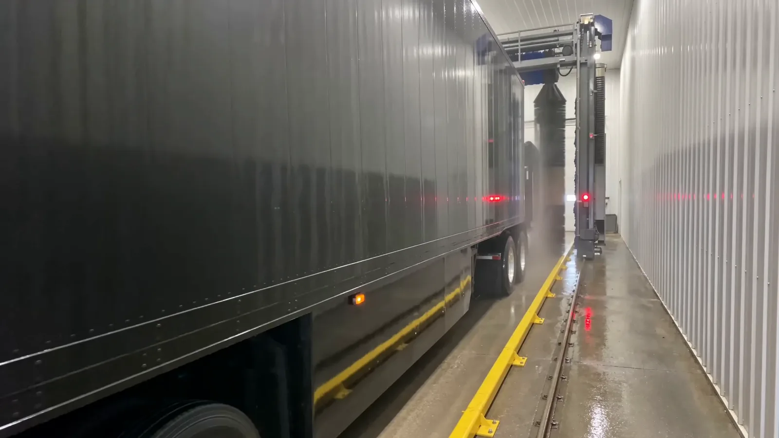 An articulated truck in a Europe Makine heavy vehicle wash, water running down the trailer